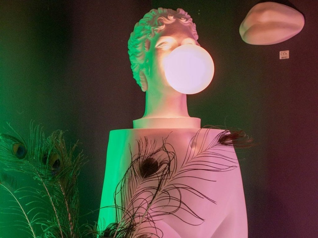 White bust with glowing orb and peacock feathers